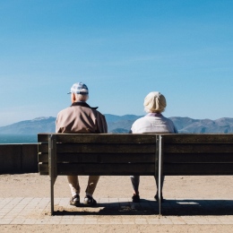 Äldre par sitter vända från varandra på en bänk.