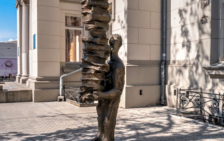 Staty som håller i stapel med böcker utanför biblitek i Odessa, Ukraina.